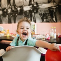 lachender Junge im Kinderstuhl